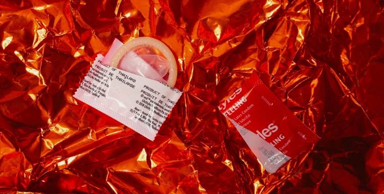 A condom and a packet on a shiny red surface

AI-generated content may be incorrect.